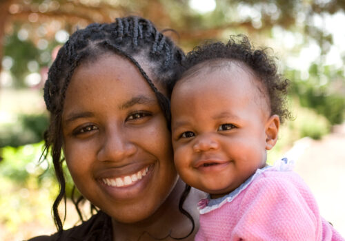 Teenage African American mother holding her daughter.